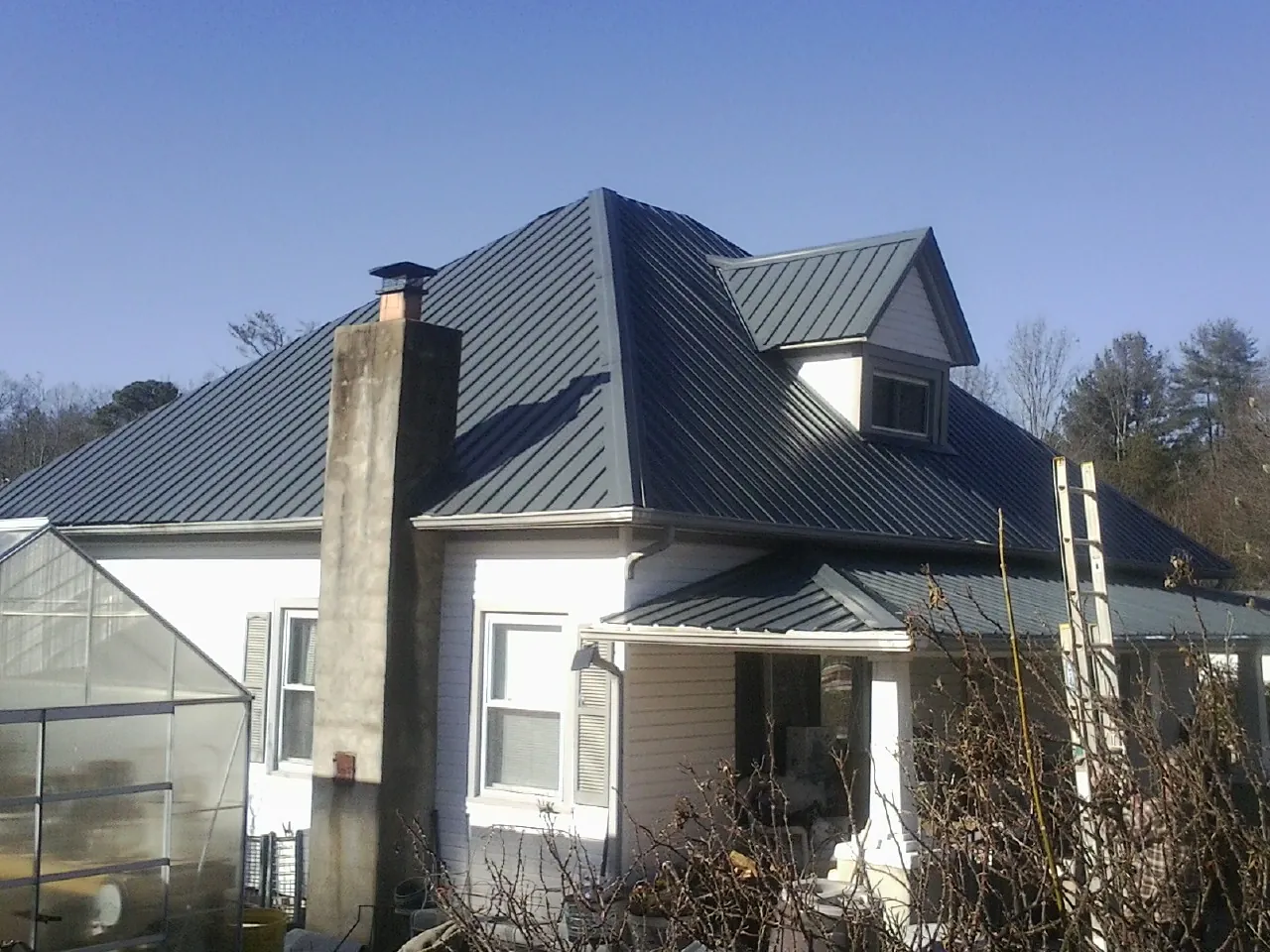 Dark blue standing seam metal roof on a white farmhouse with dormer — Slate & Tile Roof Repair by Roofing Brothers in Carol Stream