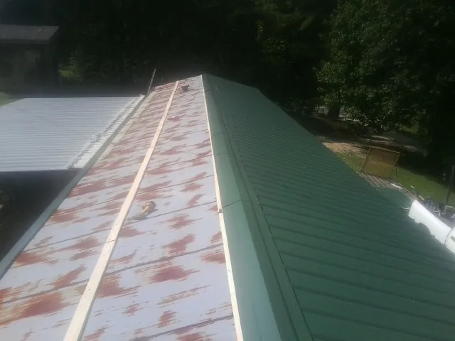 Old rusted panels beside newly installed green metal roofing — Wind Damage Roof Repair by Roofing Brothers in Carol Stream