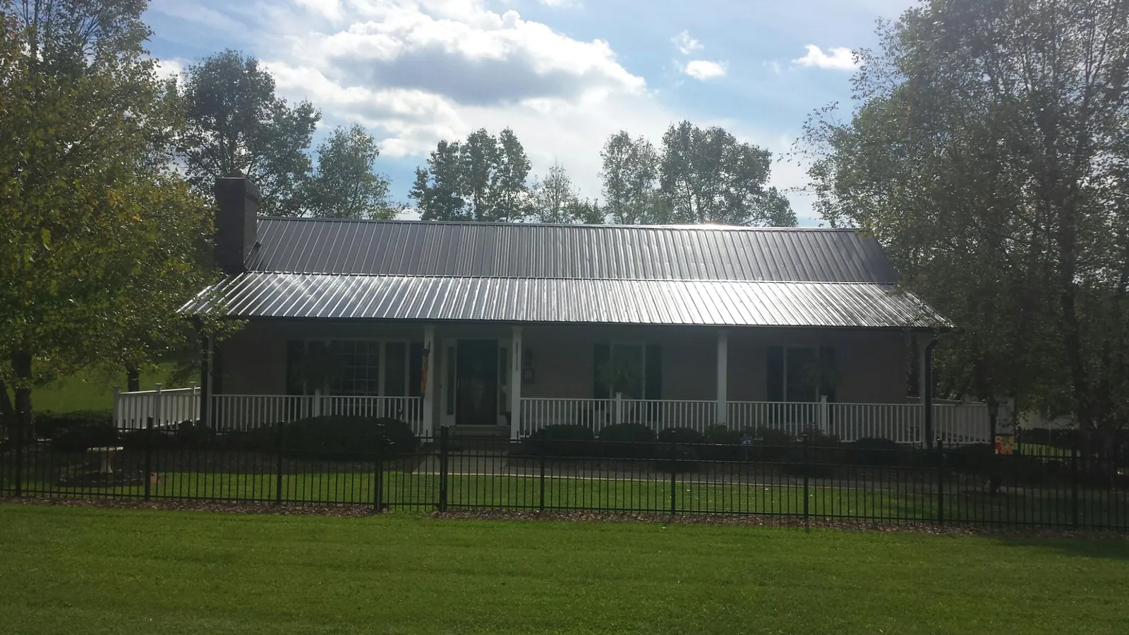 Gray metal roof on a brick ranch with a full width front porch — Gutter Guard Installation work by our crew in Carol Stream