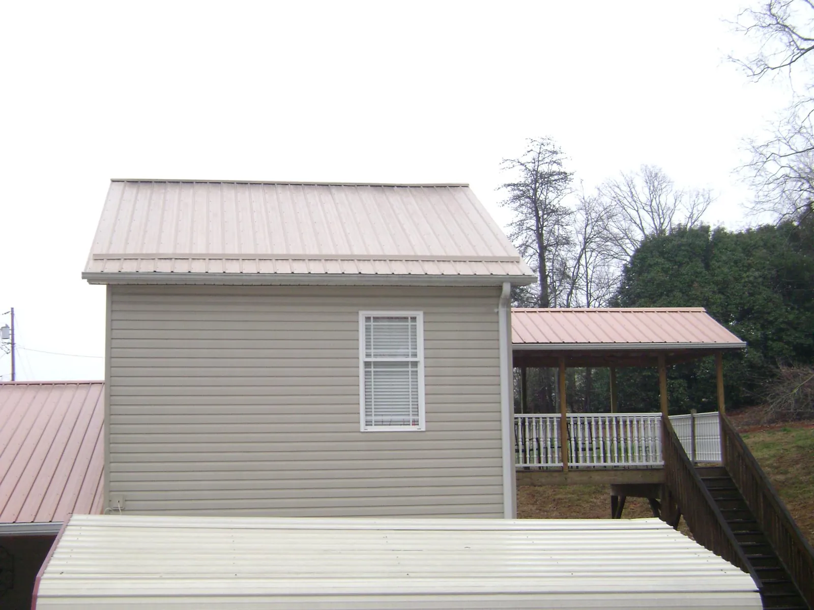 Tan metal roofs on a two story addition and attached porch, from a Roof Replacement job in Carol Stream