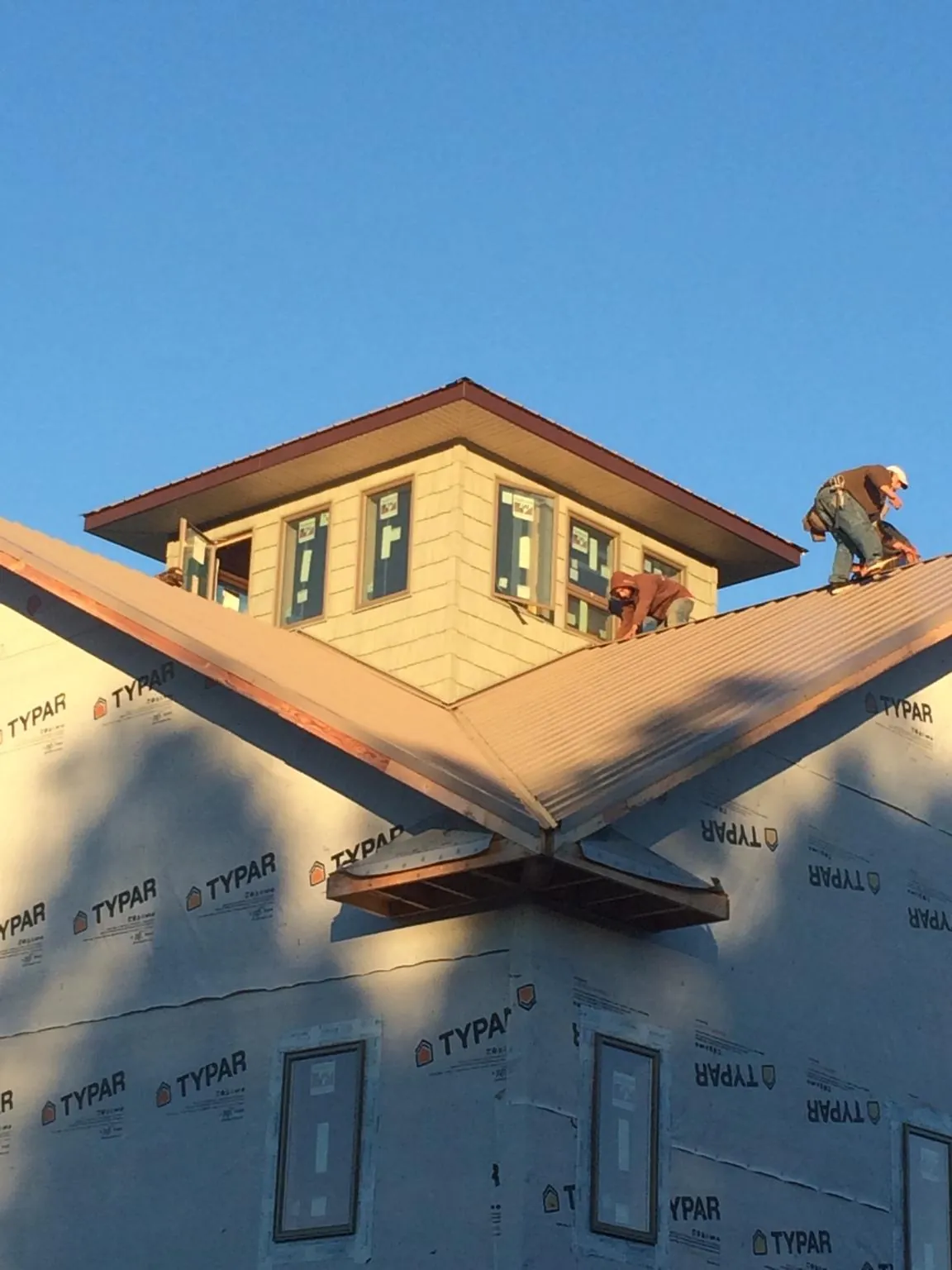 Roofers working around a rooftop cupola on a new metal roof at sunset — Roof Waterproofing in Carol Stream by Roofing Brothers